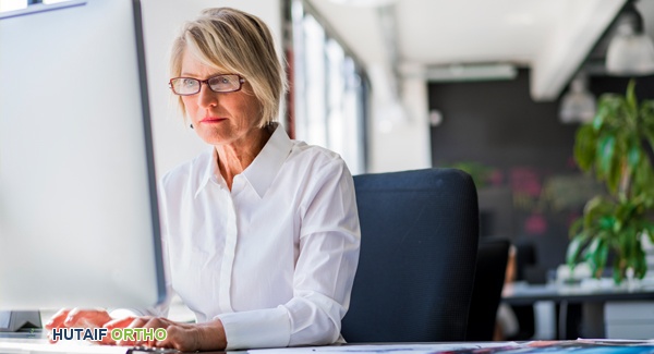 صورة توضيحية لبيئة عمل مكتبية صحية مع موظفة تعمل على جهاز كمبيوتر