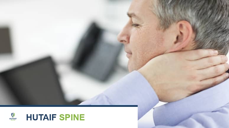 رجل يجلس على حاسوبه ويمسك رقبته بألم شديد