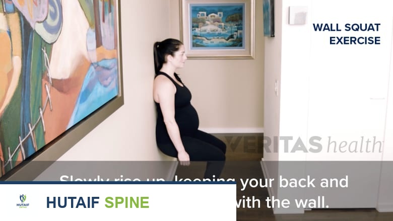 امرأة تؤدي تمرين القرفصاء على الحائط.