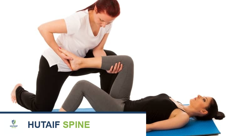 أخصائي علاج طبيعي يساعد المريض على أداء تمارين إطالة أسفل الظهر