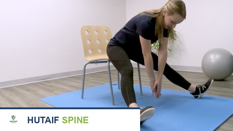 امرأة تجلس على كرسي وتؤدي تمرين إطالة العضلة المقربة للفخذ.